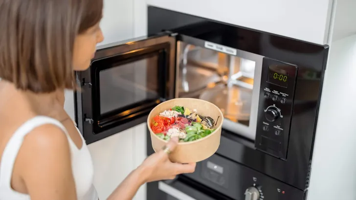 Woman heating food with microwave machine