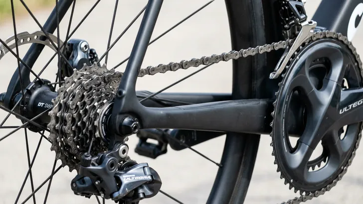Close-up van de aandrijflijn van een racefiets in een schuine 'cross-chain' positie: de ketting ligt op het grootste voorblad en het grootste achtertandwiel.