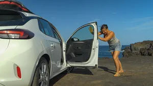 Vrouw beweegt autodeur om hete lucht uit geparkeerde auto te verdrijven