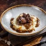 Slow cooked beef cheeks in red wine sauce with mashed potato. Dark background. Top view