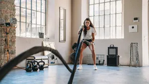 A woman is doing exercises with a rope at the gym