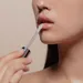 Vrouw brengt glanzende lipgloss aan voor een glossy look.