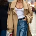 Stijlvolle trenchcoat met denim en gouden accessoires.