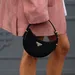 Prada koopt Versace voor ruim een miljard euro.  – Streetstyle-foto van vrouw met roze jas en Prada-handtas