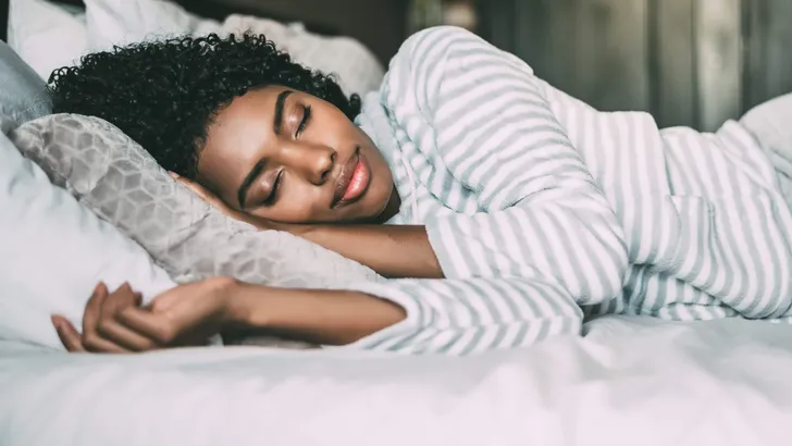 close up of a pretty black woman with curly hair sleeping in bed
