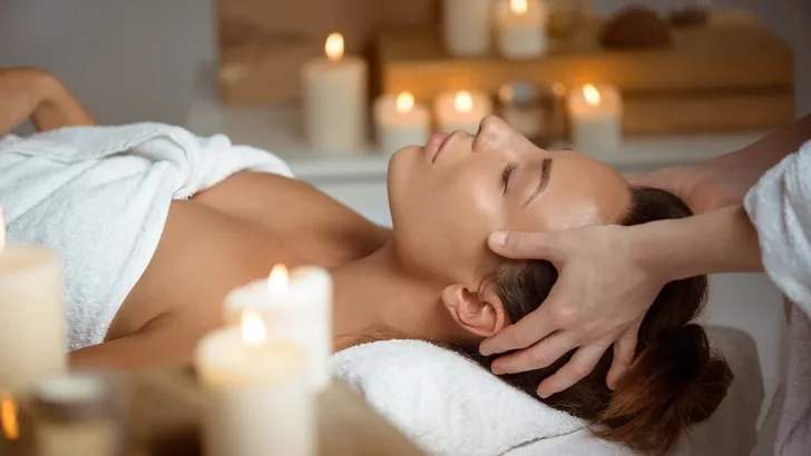 Young beautiful girl having face massage relaxing in spa salon.