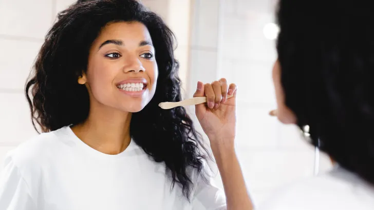 Beautiful young african-american woman brushing her teeth in the bathroom.
