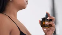 Close-up of woman spraying perfume on neck