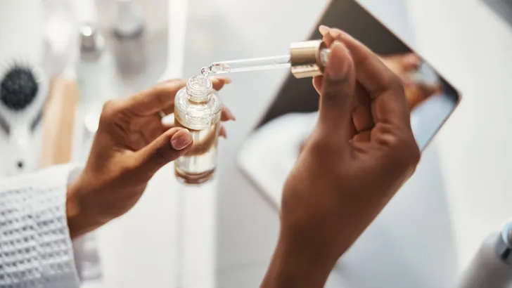 Female hands holding bottle of vitamin serum and pipette