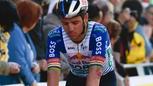 Remco Evenepoel rijdt teleurgesteld over de finishlijn met een gescheurd shirt en schaafwonden, wat de gevolgen van zijn eerdere valpartij in de Ronde van Catalonië toont.