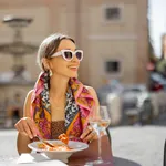 Woman eating italian pasta at restaurant on the street in Rome