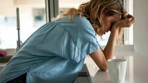 Side view of emotionally stressed mid adult woman standing in the kitchen next to a blister of pills