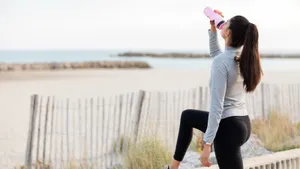 Foto van sportieve jonge vrouw die water drinkt tijdens wandeling.