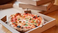 Pizza delivery concept. Baked products in a cardboard box against a wooden background. Baked tasty margherita pizza in Traditional wood oven in Neapolitan restaurant, Italy.