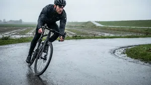 Mannelijke wielrenner met helm stuurt door een natte bocht op de racefiets om grip en bandenspanning in de regen te testen.