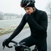 Een wielrenner in winterkleding kijkt peinzend naar zijn fietscomputer op een koude, winterse dag: moet hij een vermogensmeter aanschaffen?