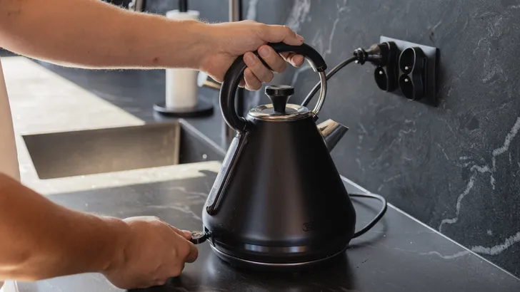 Zwarte waterkoker op aanrecht in keuken.