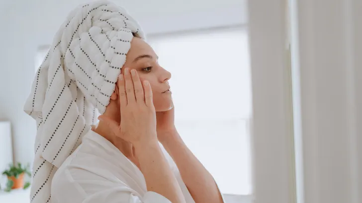 Woman applying facial cream at home