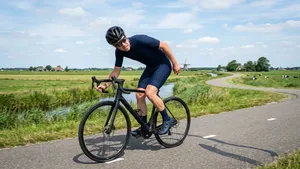 Een nerveuze wielrenner kijkt tijdens het fietsen krampachtig achterom naar zijn achterband.