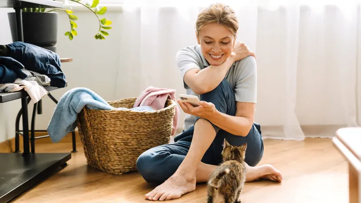 Ginger mature woman playing with kitten while doing housework