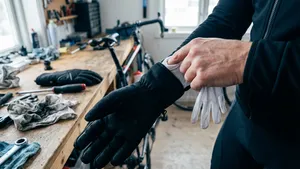 Close-up van handen die een fietshack voorbereiden: een dunne handschoen wordt in een dikke winterfietshandschoen gestopt om als extra isolatie voor de rug van de hand te dienen.