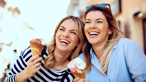 Two young women laughing and holding ice cream in hand