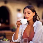 Young pretty woman enjoying drinking coffee