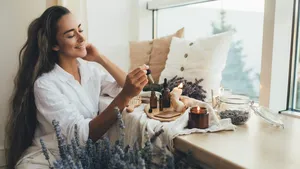 Young woman applying natural organic essential oil on hair and s