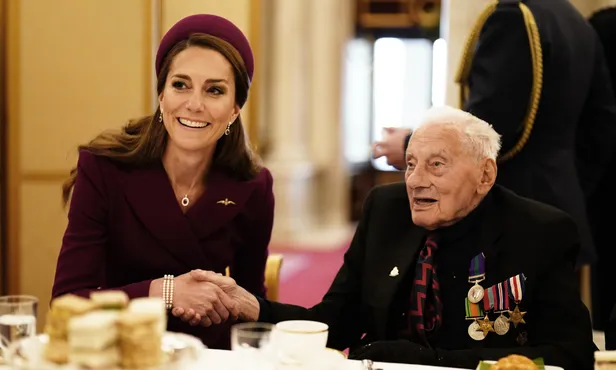Kate schudt de hand van een veteraan uit de Tweede Wereldoorlog tijdens een tea party in Buckingham Palace