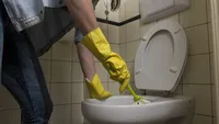 Werkster maakt het toilet schoon.