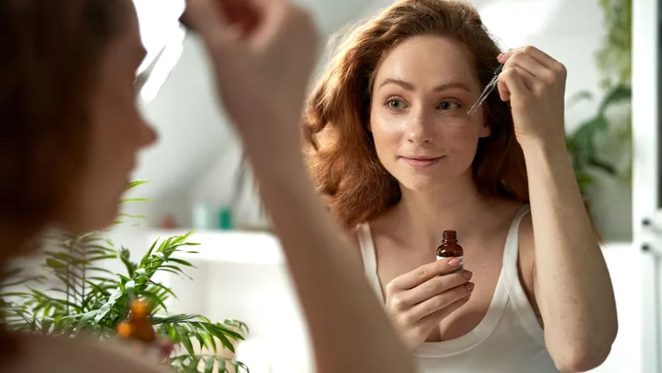 Woman using serum to face in the bathroom