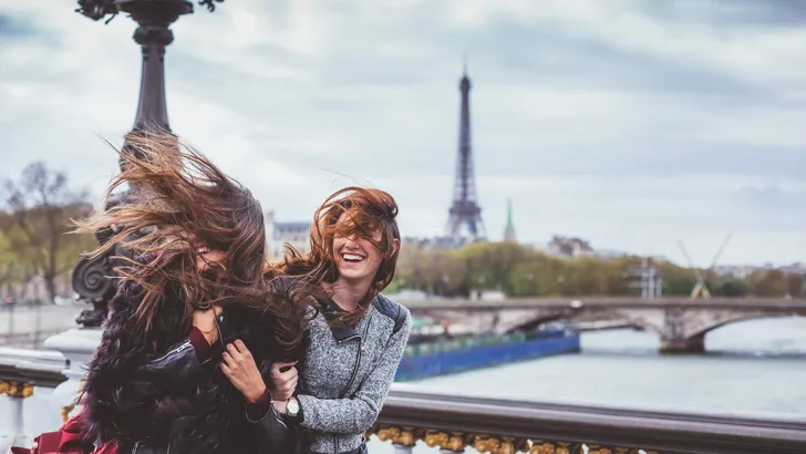 Happy friends in Paris with tousled hairs on windy day