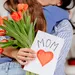 Kind geeft moeder bloemen en kaart voor moederdag