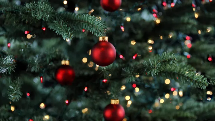 Glowing Christmas tree decorated with red and gold ornament ball