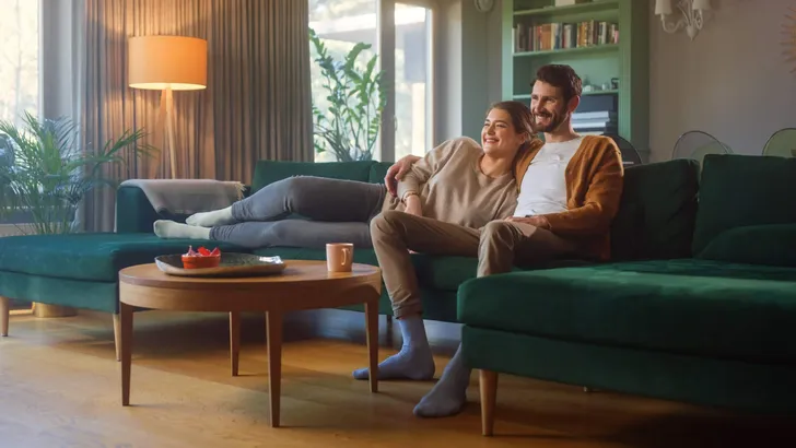 Couple Watches TV together while Sitting on a Couch in the Livin
