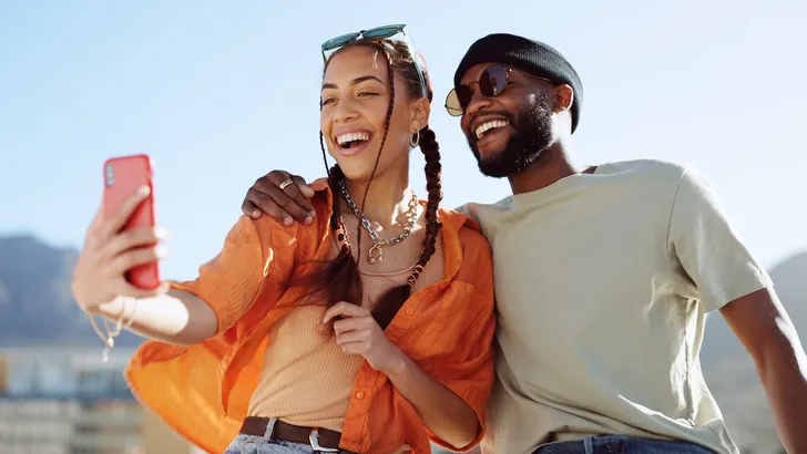 Couple, bonding and phone selfie on city building rooftop on New York summer holiday, travel vacation date or social media memory. Smile, happy or black man and woman on mobile photography technology