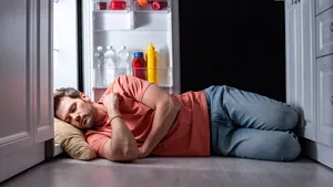 Man slaapt met zijn hoofd in de koelkast.