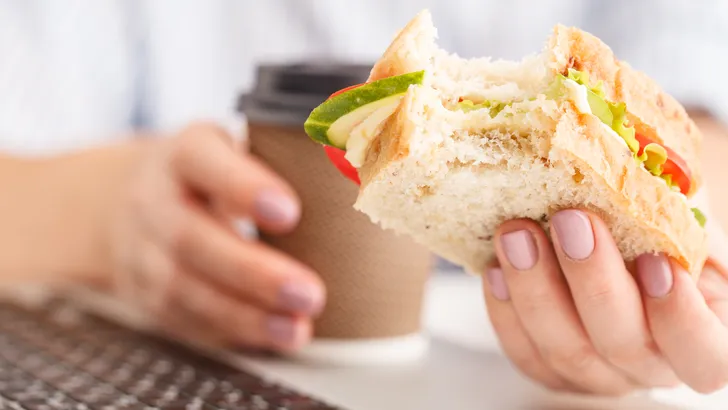 vrouw eet broodje achter haar bureau
