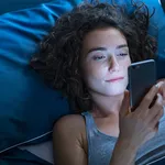 Girl awake in bed using cellphone at night