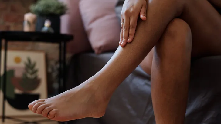 Close-up of legs of young woman touching her smooth skin