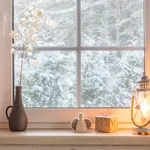 Sfeervolle brandende kaarsen en kerstverlichting op de vensterbank binnen.