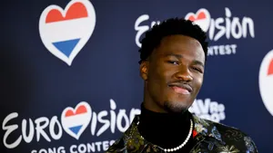 Dit is het Songfestival-nummer van Claude. – Foto van Claude bij het logo van het Eurovisie Songfestival met een Nederlandse vlag, december 2024.