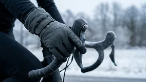 Close-up van wielrenner met dikke winterhandschoenen die elektronisch schakelt op een racefiets tijdens een koude winterrit.