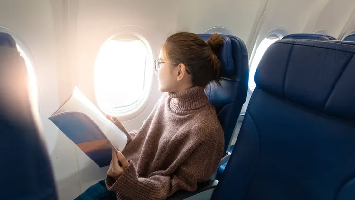 Beautiful Asian woman is reading magazine in airplane