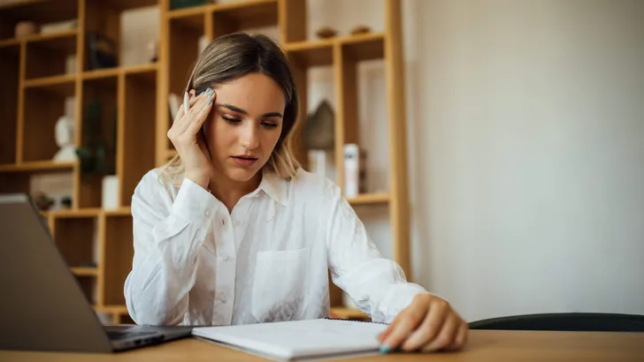 Portrait of a worried young woman studying or reading.