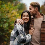 Beautiful happy couple smiling and hugging while strolling in forest