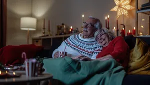 Een ouder echtpaar kijkt tijdens de kerstvakantie een film, zittend op de bank.