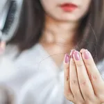 woman hand holding hair fall from hairbrush