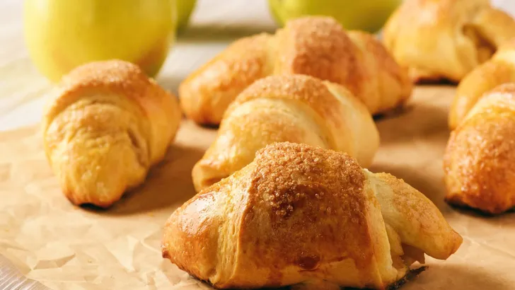 Croissants with apple jam on wooden background.