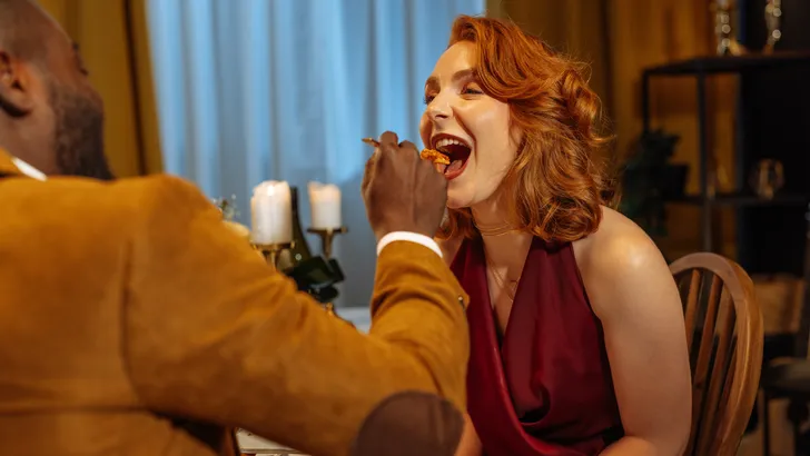 Stel geniet van een romantisch diner tijdens Valentijn; de man voert de vrouw een hapje van het heerlijke eten.